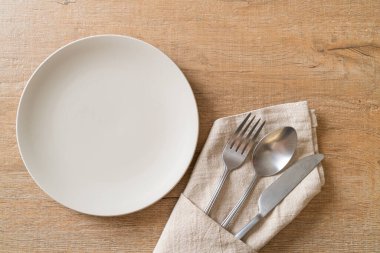 Ahşap zemin üzerinde bıçak, çatal ve kaşık olan boş tabak veya tabak