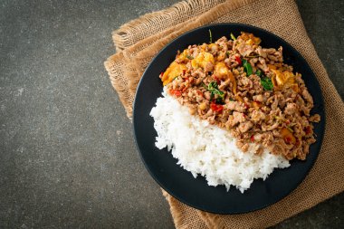 Pirinçli yumurta ve fesleğenli kızarmış domuz eti. Asya usulü.