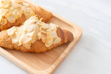 Kremalı kruvasan ve ahşap tabakta badem.