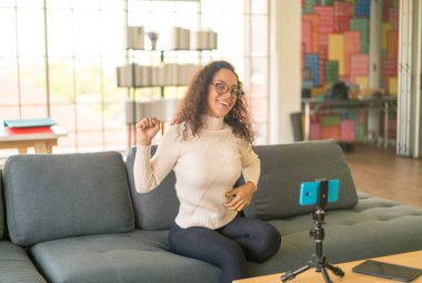 Latin kadın etkileyicisi video çekiyor ve blog için kamerayla konuşuyor - çevrimiçi içerik kavramı