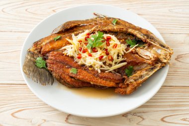 Balık soslu kızarmış deniz levreği balığı ve tabakta baharatlı salata.