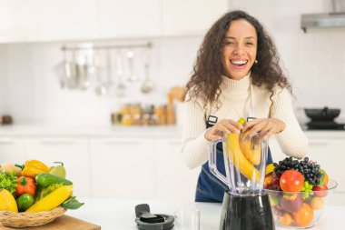 Latin kadın, vejetaryen yemeği için mutfakta meyve suyu yapıyor.