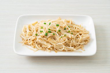 Karıştırılmış altın iğneli mantar, beyaz tabakta tereyağı.