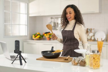 Latin kadın blogda paylaşmak için mutfakta video ve yemek çekiyor.