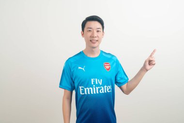 Bangkok, THAILAND - 27 Kasım 2021: beyaz arka planda Arsenal tişörtü giyen genç Asyalı. Arsenal, Londra 'nın en ünlü futbol kulübüdür..