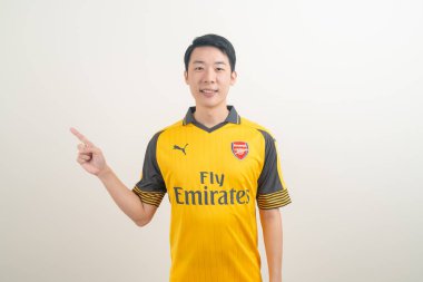 Bangkok, THAILAND - 27 Kasım 2021: beyaz arka planda Arsenal tişörtü giyen genç Asyalı. Arsenal, Londra 'nın en ünlü futbol kulübüdür..