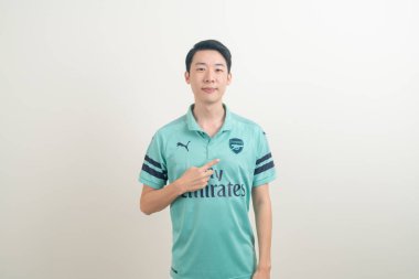 Bangkok, THAILAND - 27 Kasım 2021: beyaz arka planda Arsenal tişörtü giyen genç Asyalı. Arsenal, Londra 'nın en ünlü futbol kulübüdür..