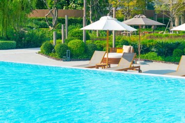 Okyanus geçmişi olan yüzme havuzunun etrafında havuzu olan şemsiyeler - tatil ve tatil kavramı