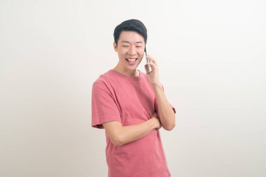 Genç Asyalı adam beyaz arka planda mutlu yüzlü akıllı telefon ve cep telefonu kullanıyor veya konuşuyor