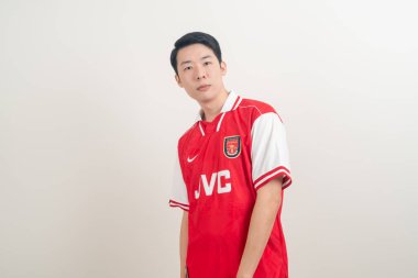 Bangkok, THAILAND - 27 Kasım 2021: beyaz arka planda Arsenal tişörtü giyen genç Asyalı. Arsenal, Londra 'nın en ünlü futbol kulübüdür..