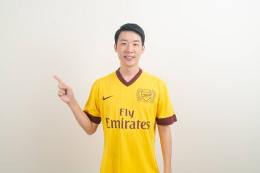 Bangkok, THAILAND - 27 Kasım 2021: beyaz arka planda Arsenal tişörtü giyen genç Asyalı. Arsenal, Londra 'nın en ünlü futbol kulübüdür..