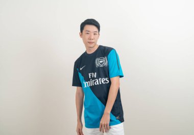 Bangkok, THAILAND - 27 Kasım 2021: beyaz arka planda Arsenal tişörtü giyen genç Asyalı. Arsenal, Londra 'nın en ünlü futbol kulübüdür..