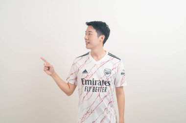 Bangkok, THAILAND - 27 Kasım 2021: beyaz arka planda Arsenal tişörtü giyen genç Asyalı. Arsenal, Londra 'nın en ünlü futbol kulübüdür..
