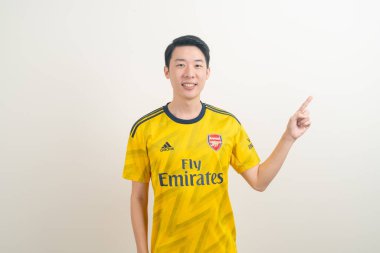Bangkok, THAILAND - 27 Kasım 2021: beyaz arka planda Arsenal tişörtü giyen genç Asyalı. Arsenal, Londra 'nın en ünlü futbol kulübüdür..
