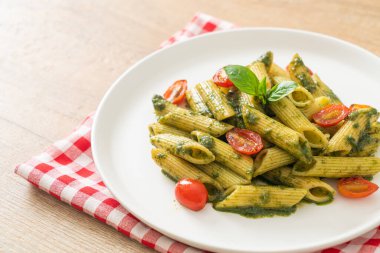 Pesto soslu ve domatesli makarna. Vejetaryen ve vejetaryen yemek tarzı.
