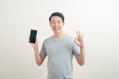 Beyaz arka planda akıllı telefon ve cep telefonu kullanan ya da konuşan genç Asyalı adam