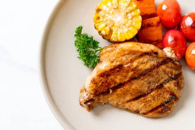 Izgara ve ızgara fileto domuz bifteği, mısır, havuç ve domates.