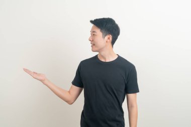 Beyaz arka planda eli işaret eden ya da sunan genç Asyalı adam portresi