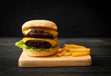 Peynirli ve patates kızartmalı hamburger veya sığır burger. Sağlıksız yemek tarzı.