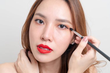 Beyaz arka planda makyaj fırçası olan güzel Asyalı kadın portresi.