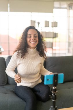 Latin kadın etkileyicisi video çekiyor ve blog için kamerayla konuşuyor - çevrimiçi içerik kavramı