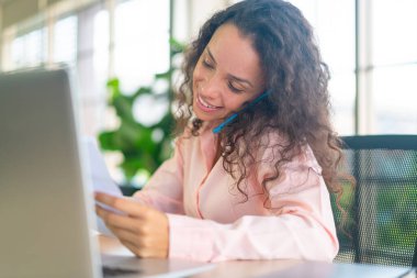 Evde çalışan Latin bir kadın telefonla çalışıyor.