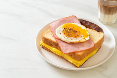 Ev yapımı ekmek üzerine kızarmış peynir jambon ve kızarmış yumurta ile domuz sosisi ve kahvaltıda kahve.