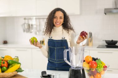 Latin kadın, vejetaryen yemeği için mutfakta meyve suyu yapıyor.