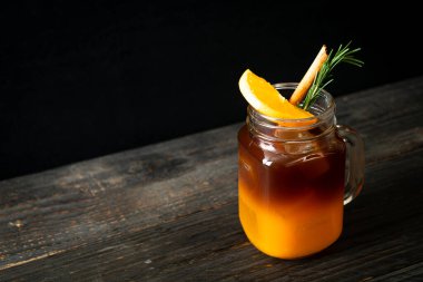 Bir bardak buzlu americano sade kahve ve biberiye ve tarçınla süslenmiş portakal ve limon suyu.