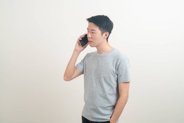 Beyaz arka planda akıllı telefon ve cep telefonu kullanan ya da konuşan genç Asyalı adam