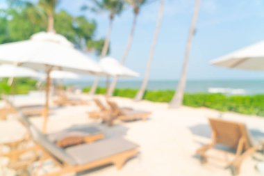 Arka planda plaj sandalyesi ve okyanus denizi olan soyut bulanık şemsiye