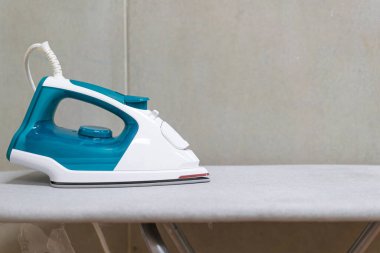 Gri arkaplanı olan ütü masasında beyaz ütü