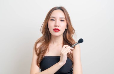Beyaz arka planda makyaj fırçası olan güzel bir Asyalı kadın portresi