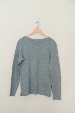 grey t-shirt hanging with wood hanger on wall