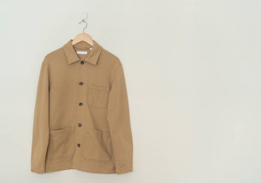 beige suit hanging with wood hanger on wall
