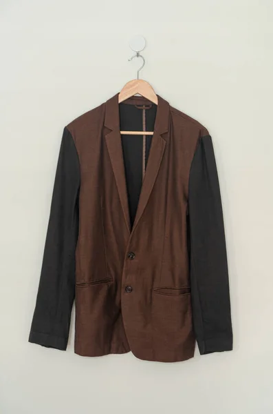 dark brown suit hanging with wood hanger on wall