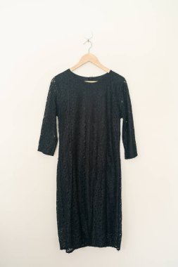 beautiful black dress hanging with wood hanger on wall