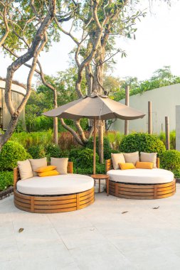 Bahçedeki şemsiyeli teras sandalyesinde yastıklar.