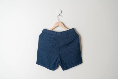 Kısa pantolon duvarda ahşap bir askıyla asılı.