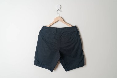 Kısa pantolon duvarda ahşap bir askıyla asılı.