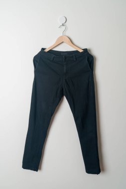 Pantolonlar duvarda ahşap bir askıyla asılı.