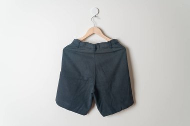 Kısa pantolon duvarda ahşap bir askıyla asılı.