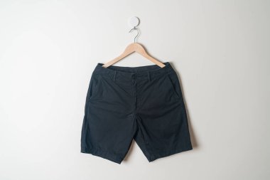 Kısa pantolon duvarda ahşap bir askıyla asılı.