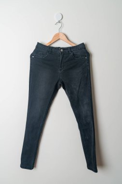 Pantolonlar duvarda ahşap bir askıyla asılı.