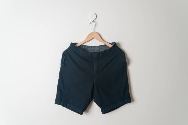Kısa pantolon duvarda ahşap bir askıyla asılı.