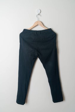 Pantolonlar duvarda ahşap bir askıyla asılı.