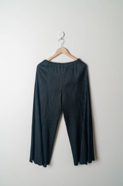 Pantolon ya da uzun pantolon duvarda ahşap askıyla asılı.