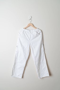 Pantolon ya da uzun pantolon duvarda ahşap askıyla asılı.