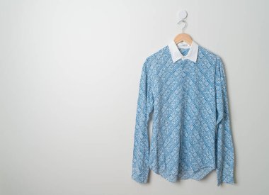 hanging blue shirt with wood hanger on wall