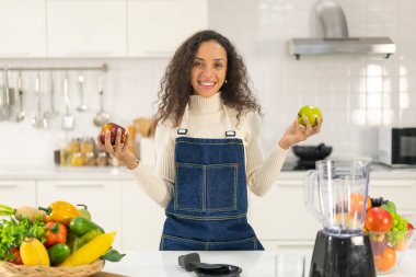 Latin kadın, vejetaryen yemeği için mutfakta meyve suyu yapıyor.